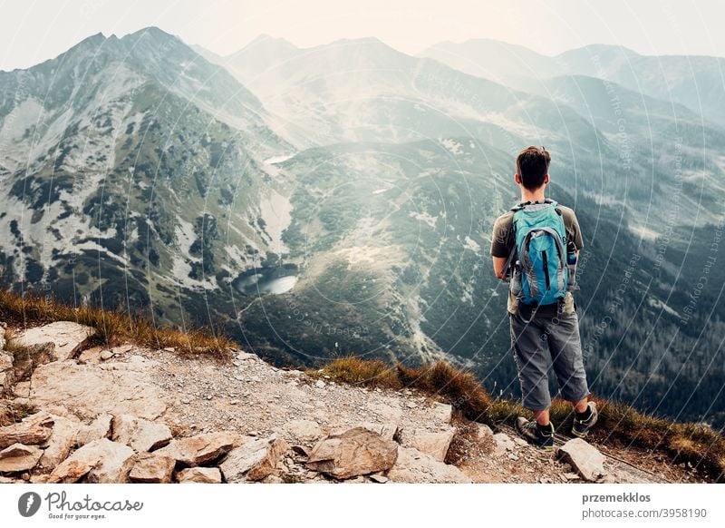 Young man with backpack hiking in a mountains, actively spending summer vacation activity adventure freedom healthy joy leisure nature park recreation spring