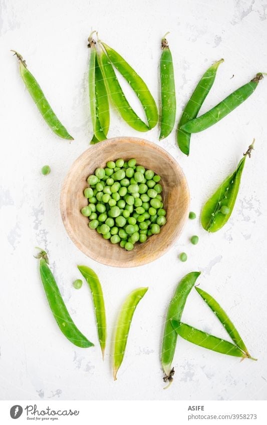 Green peas in a bowl and pods on a rough white background green peas raw fresh vegetable healthy food peeling top view from above flat lay diet vegetarian vegan
