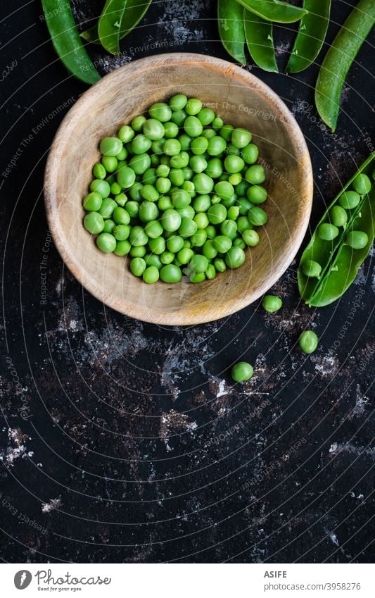 Green peas in a bowl and pods on a rough dark background green peas raw fresh vegetable healthy food peeling top view from above flat lay diet vegetarian vegan