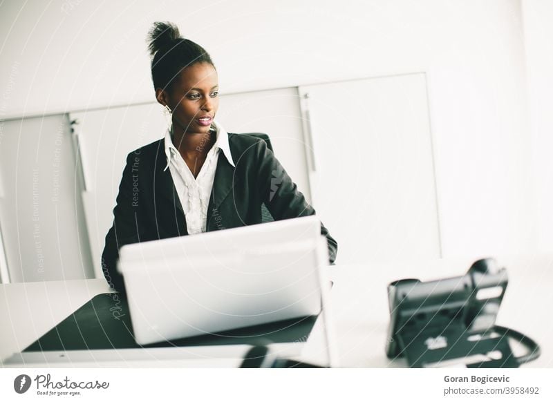 Young woman in the office female desk person adult sitting computer black african young occupation professional working looking indoors 20s corporate