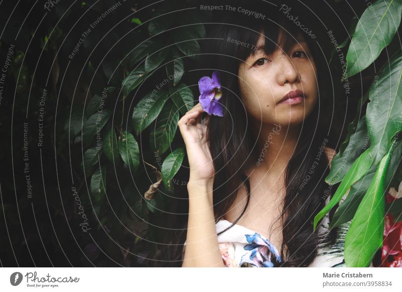 A woman among the thick green foliage showing concept of wellness in nature, mindfulness and mental wellbeing lady plant clean natural dark and moody