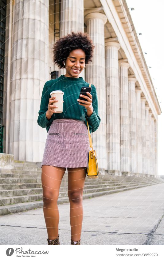 Business woman using her mobile phone outdoors. afro business black modern style brunette gadget positive concept connection application sms texting