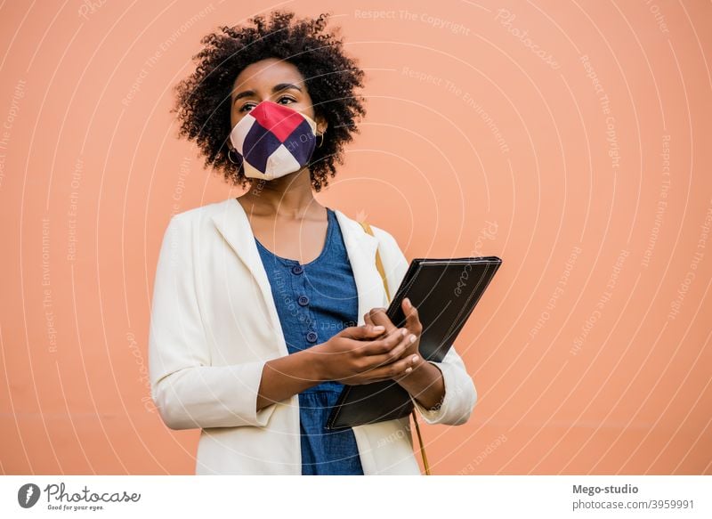 Afro businesswoman standing outdoors on the street. afro protective mask profession drinking pandemic businessperson concept beverage corporate lifestyle