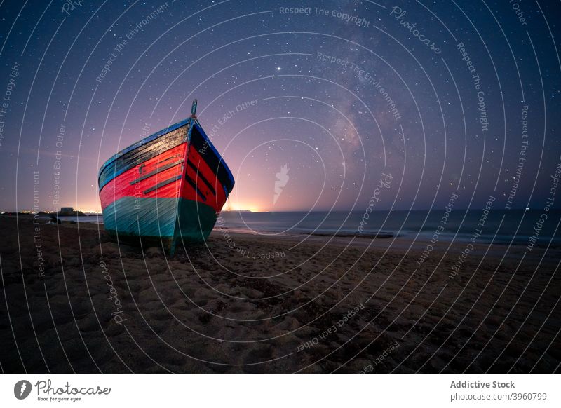 Wooden boat on beach at night star sky starry galaxy wooden vessel sea cadiz spain andalucia sand water serene twilight evening milky way constellation shore