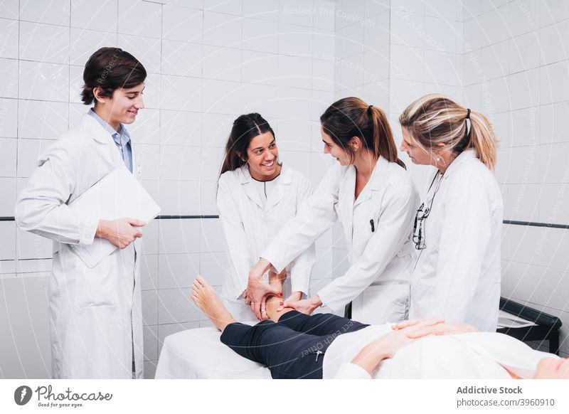 smiling group of doctors are examining the leg of a patient in a hospital CrotoChic analysis analyzing anatomy bone clinic coat diagnosis examination examine