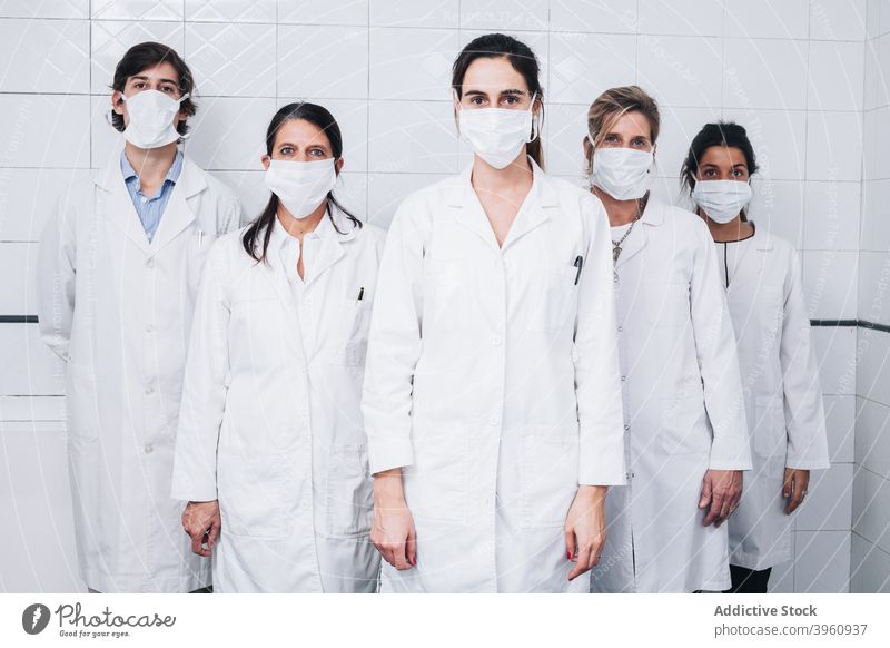 A group of doctors with a mask on the face and uniform standing up in a hospital CrotoChic checking clinic coat consultant coronavirus covid employment five flu