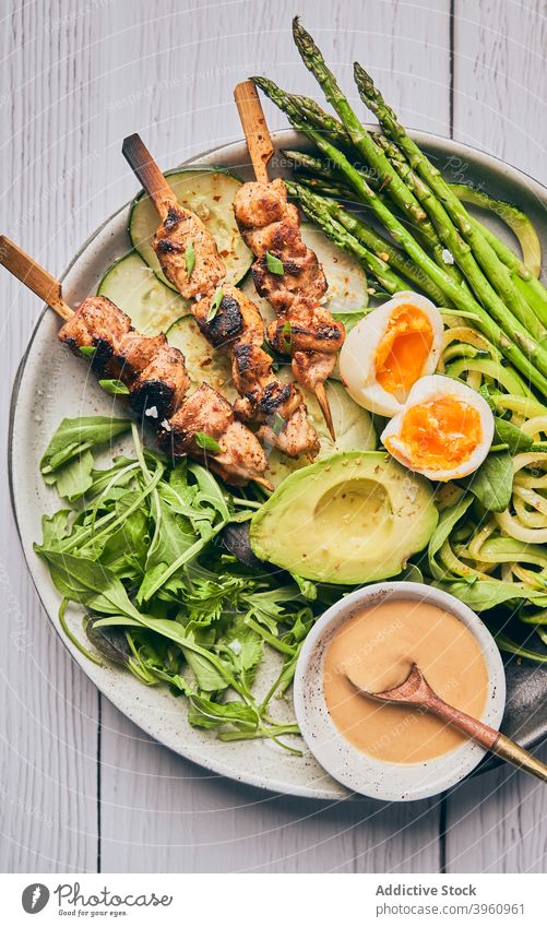 Plate with meat on wooden skewers and various vegetables on table plate chicken assorted sauce dish kebab food delicious tasty ingredient fresh cuisine avocado