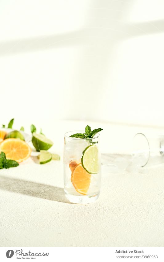Glass of fresh cocktail with lime and lemon water infuse drink lemonade refreshment mint citrus beverage slice mojito garnish delicious summer white table sprig