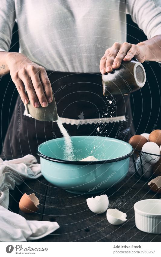 Crop woman mixing ingredients for pastry in bowl cook dough pour sugar flour kitchen female add food recipe apron culinary table cuisine homemade prepare