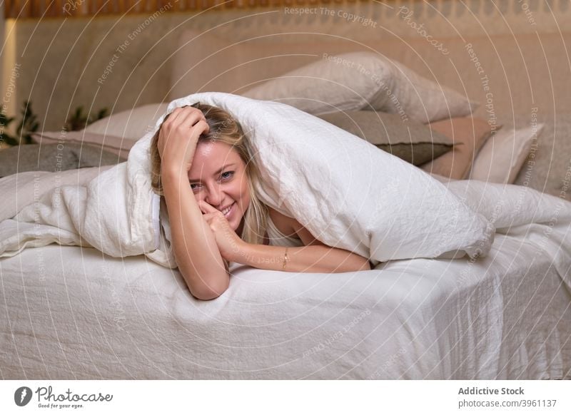 Content woman relaxing on bed at home chill bedroom weekend rest cheerful soft comfort duvet female blanket lying delight joy young glad enjoy apartment content