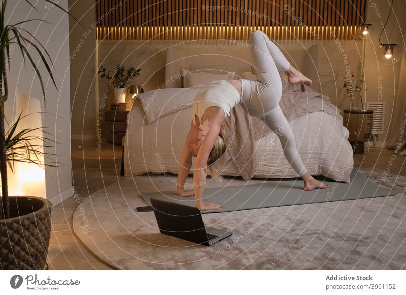 Woman standing in Wheel pose on yoga mat wheel pose woman flexible practice tutorial asana stretch laptop home female online lesson mindfulness zen gadget
