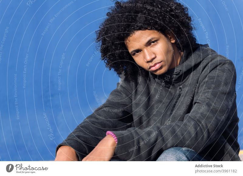 Pensive hipster teen guy near blue wall man teenage thoughtful serious pensive curly hair afro informal millennial male black african american ethnic attitude