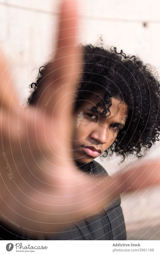 Black male teenager with protesting gesture man no outstretch hand stop serious young confident attitude cover african american black ethnic curly hair