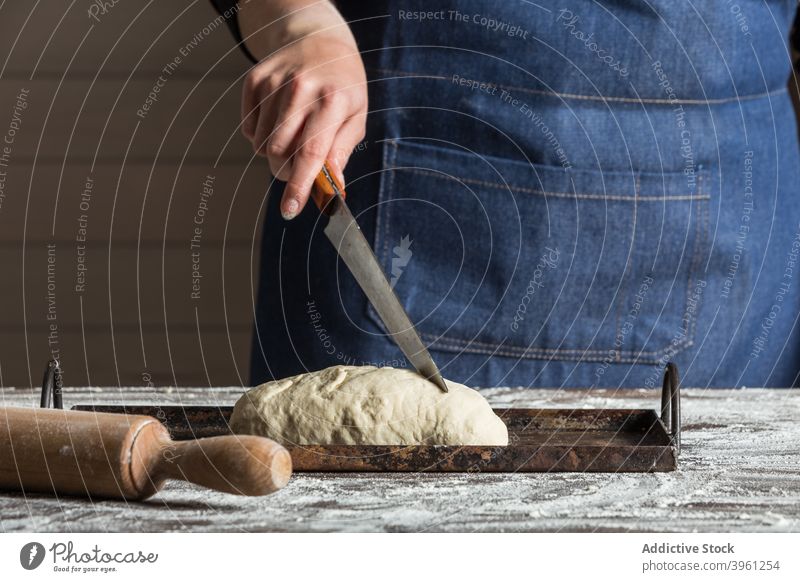 Baker cutting dough for bread baker knife food prepare flour bakery artisan kitchen culinary female cook pastry cuisine chef process small business occupation