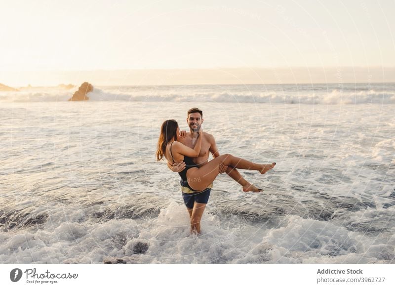 Happy couple having fun in foamy sea waves romantic love beach together happy sunset water fondness young tenerife island canary spain embrace relationship