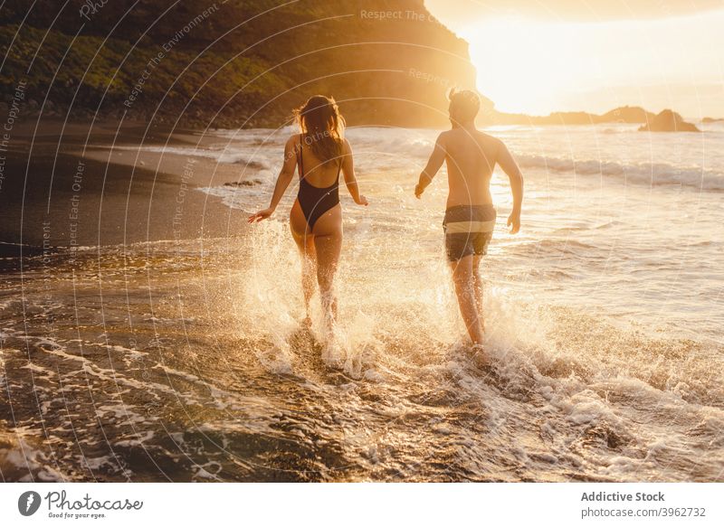 Romantic couple walking on foamy sea waves sunset romantic love beach together happy ocean having fun holding hands coast fondness young tenerife island canary
