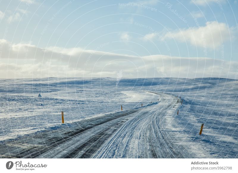 Snowy road on sunny day in winter snow empty roadway landscape endless scenery iceland terrain blue sky cloudy cold nature season weather scenic frost