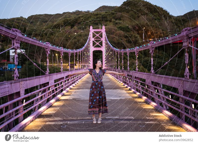 Carefree ethnic woman on bridge in evening summer vacation suspension carefree enjoy twilight footbridge female asian taiwan delight cheerful happy relax dusk