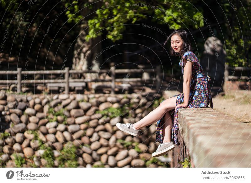 Smiling ethnic woman sitting on bridge in summer forest vacation carefree smile cheerful aged landmark female asian daping red bridge taiwan relax brick