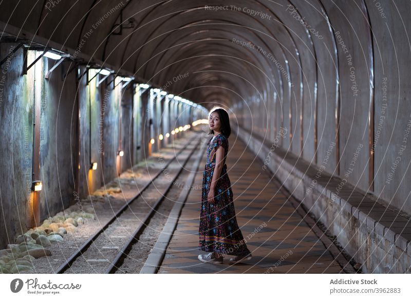 Ethnic woman standing in shabby arched tunnel archway old dress tourist landmark destination female ethnic asian old baiji tunnel taiwan maxi young travel aged