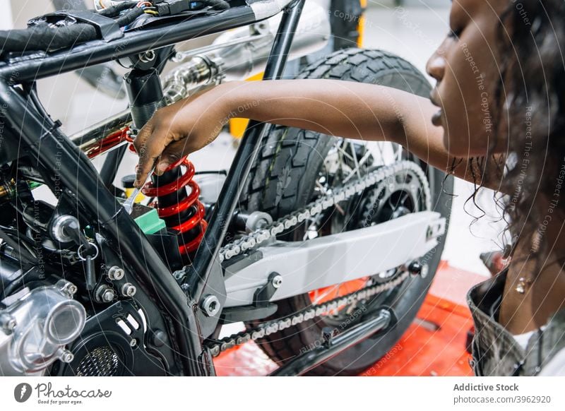 African Female auto mechanic work in garage, car service technician woman  in overalls check and repair customer car at automobile service center,  inspecting car under body and suspension system Stock-Foto