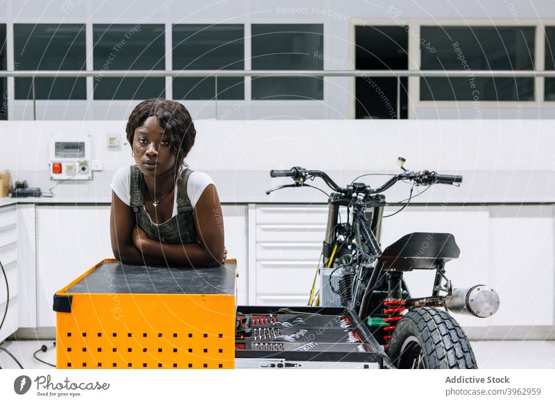Black woman with motorcycle working in workshop mechanic motorbike custom professional vehicle repair assemble female african american black ethnic job
