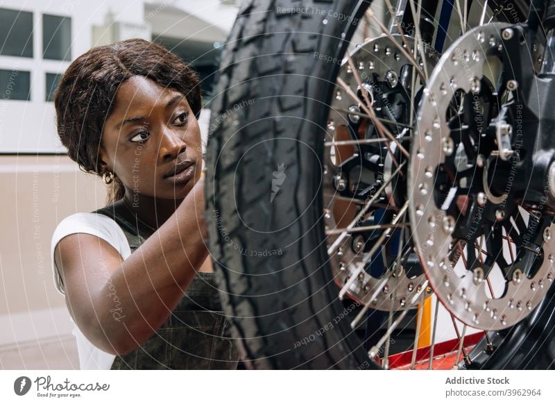Professional female master fixing wheel of motorbike woman mechanic motorcycle custom workshop professional tire vehicle repair assemble african american black