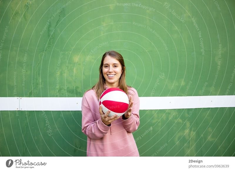 young long haired woman holding a basket ball against green wall sport person basketball fitness training athlete female girl player exercise healthy lifestyle
