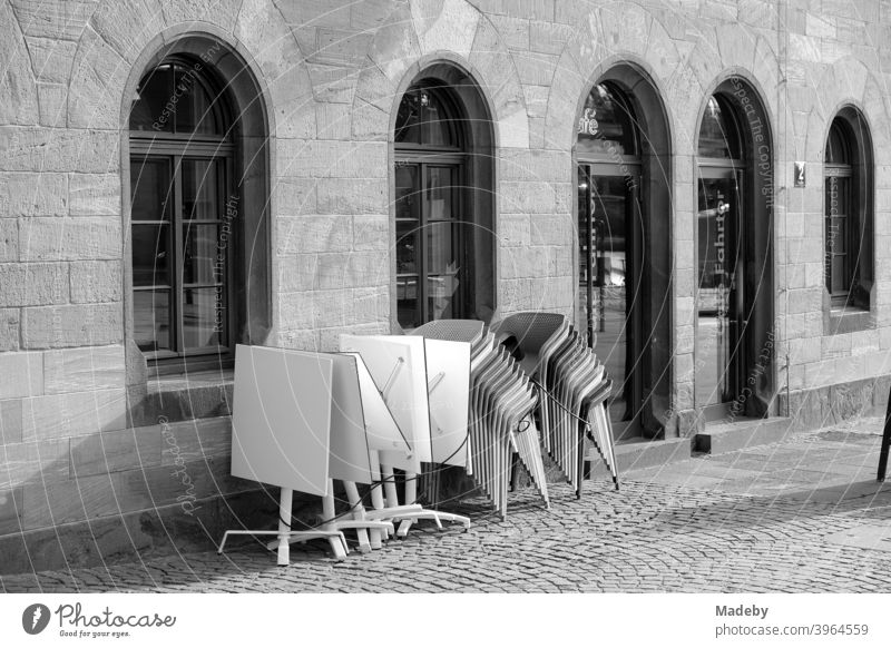 Folded tables and stacked chairs in front of a bristro with round arch windows on the Römerberg in Frankfurt am Main in Hesse Restaurant Gastronomy Tavern