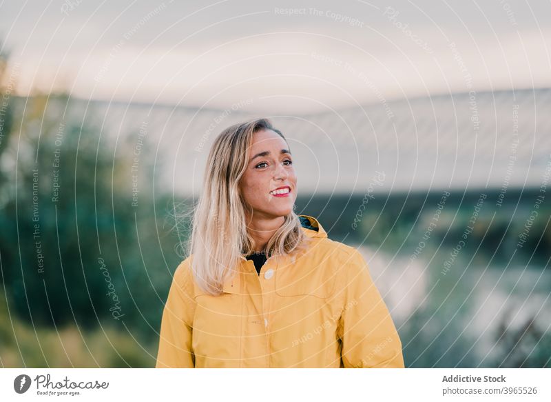 Cheerful woman standing in park yellow raincoat smile weekend enjoy city outerwear outfit female cheerful delight carefree nature charming season optimist glad