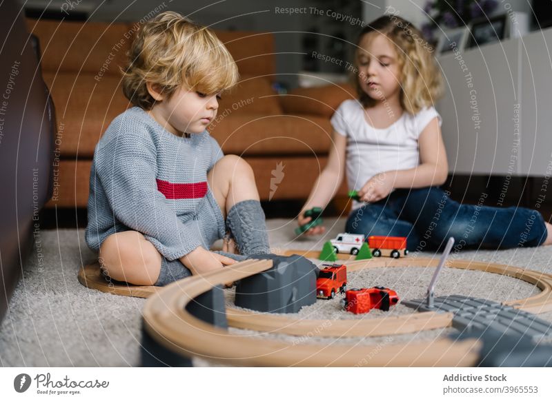 Kids playing with toy track game together kid sibling children car little activity childhood road lifestyle preschool free time creative curly hair childcare