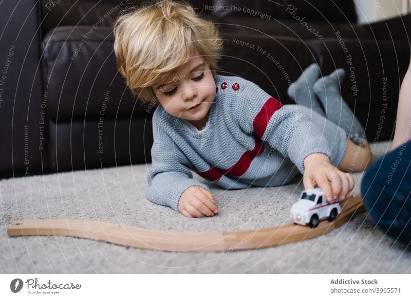 Happy kid playing with toy at home boy child game car activity happy cute little lying childhood lifestyle preschool free time childcare enjoy recreation