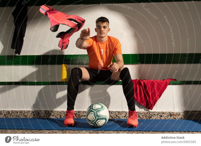 A football player in dressing room with sports uniform man sittimg peolple soccer interior sneakers bench sportswear sporty training workout activity stuff