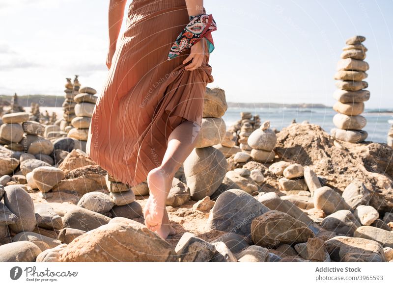 Trendy young lady resting on sandy coast amidst stones in daytime woman relax beach style vacation holiday nature traveler feminine recreation female trendy