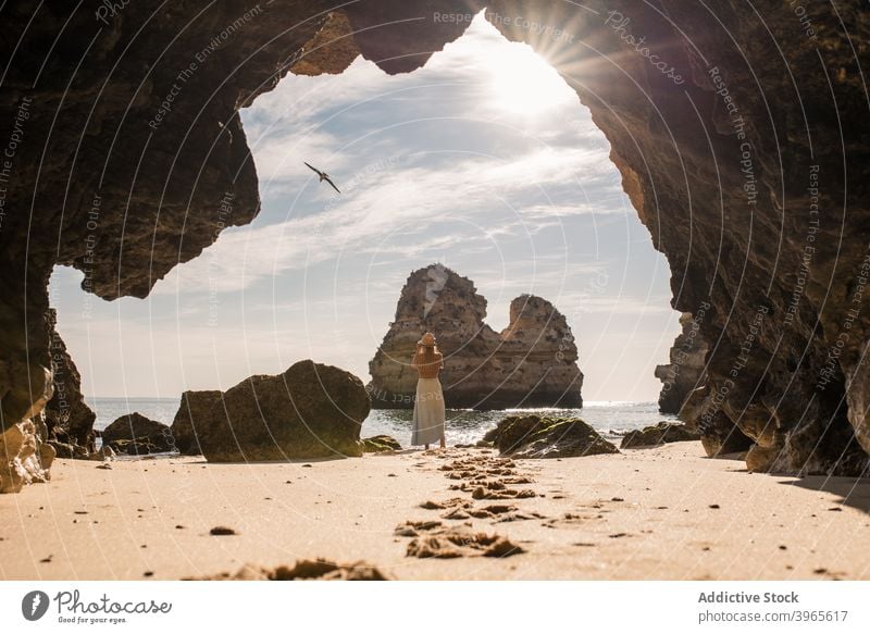 Anonymous woman in cave near sea shore nature sand entrance romantic vacation algarve portugal female ocean travel beach coast relax hat casual trip lifestyle