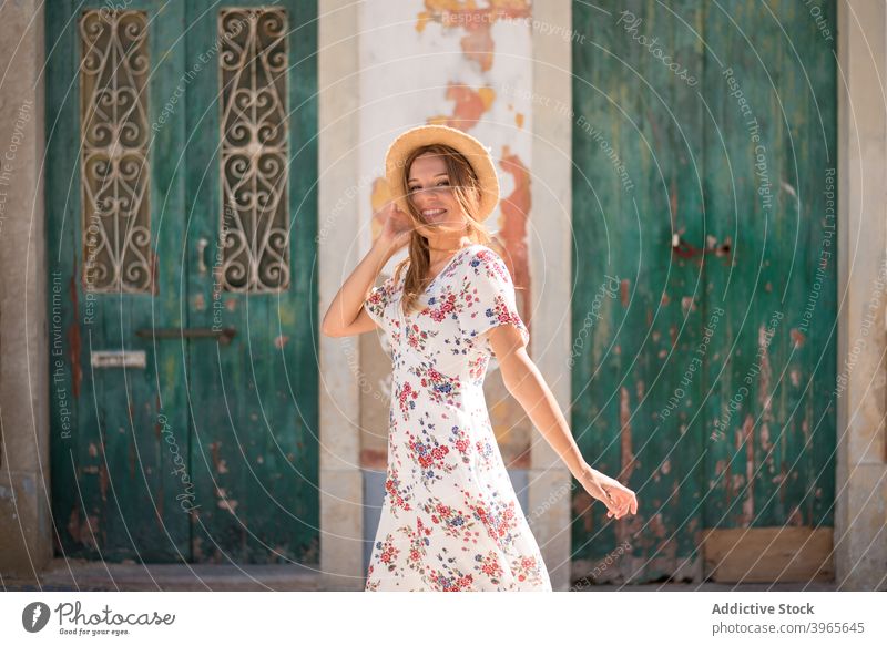 Female traveler standing on the street near old building in Algarve woman house explore sightseeing summer holiday wanderlust female young blond dress straw hat