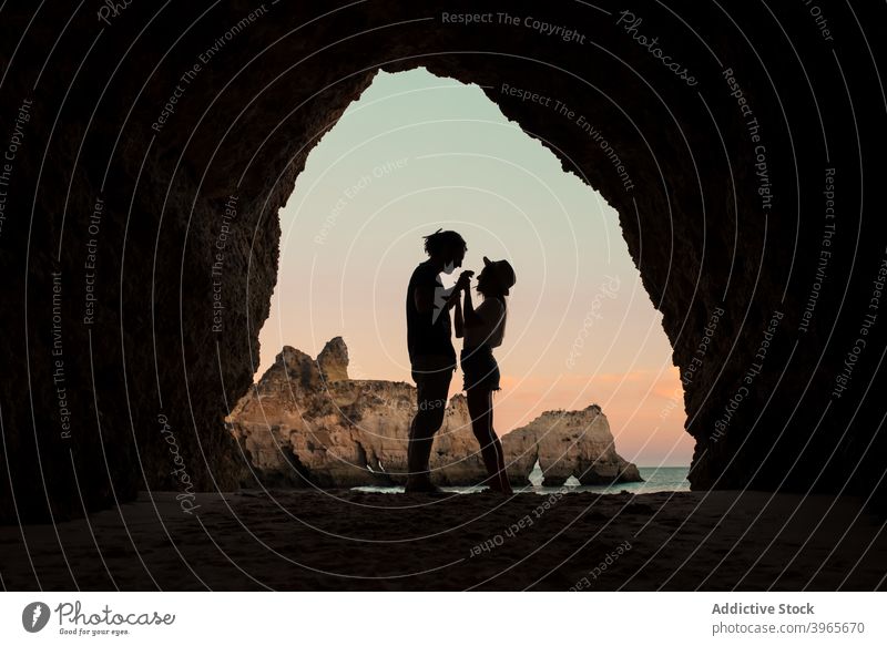 Anonymous couple standing in cave entrance sea love evening man woman algarve portugal embrace romantic relationship ocean together boyfriend girlfriend