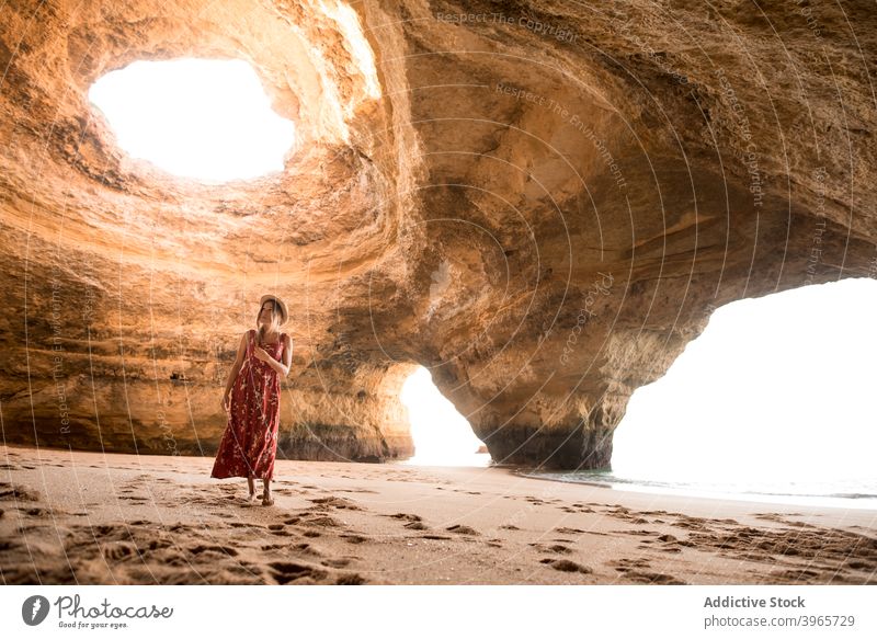 Woman walking in cave near sea woman summer sunny daytime sand stone travel algarve portugal spacious rock shore coast ocean vacation tourism water nature