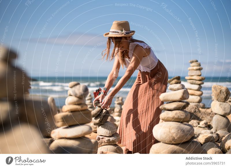Happy young female tourist creating zen stones on sandy beach in sunlight woman pyramid smile cheerful enjoy ocean vacation traveler holiday happy style