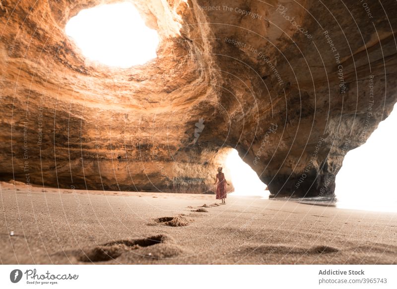 Anonymous woman walking in cave near sea summer sunny sand stone travel algarve portugal rock shore coast ocean vacation tourism water nature wanderlust