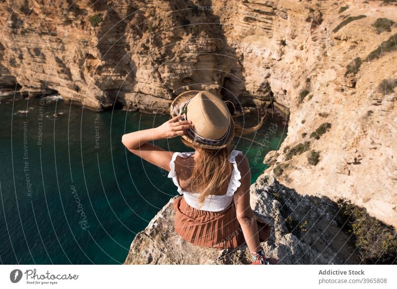 Anonymous woman in summer clothes sitting in cliff coastline rocky mountain holidays mediterranean horizon admiring seaside young tourism female saint vincent