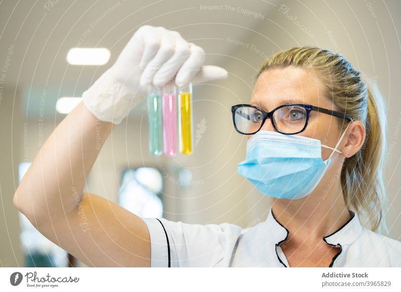 Scientist with test tubes in laboratory scientist woman flask chemical liquid glass sample female mask latex serious various experiment colorful varicolored
