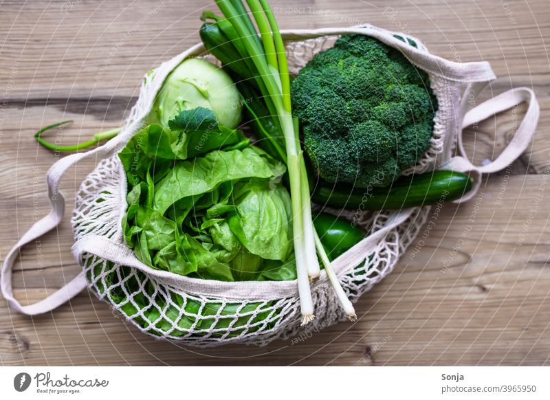 Raw green vegetables in a reusable net shopping bag on a wooden table Vegetable Green Fresh Diet Vegetarian diet Background picture Table Wood Organic Reusable