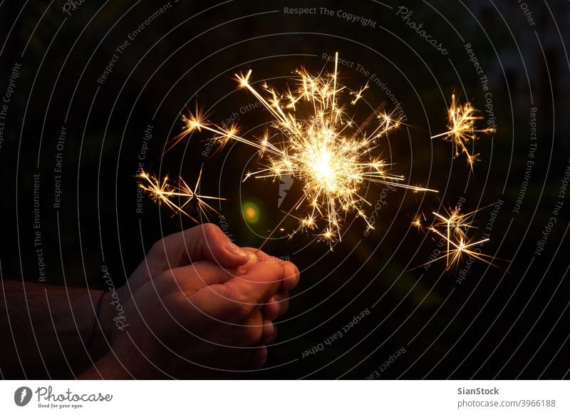 Close up of man hands holding sparkler gold person celebration fire holiday party christmas festive light night new year firework xmas bengal dark beautiful