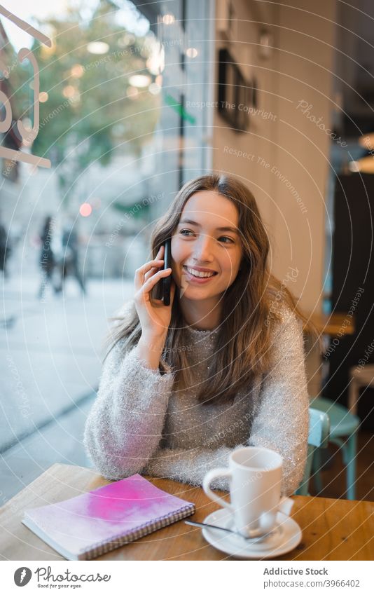 Woman talking on smartphone in cafe woman smile discuss speak cafeteria relax chill female device table charming cheerful content connection modern conversation