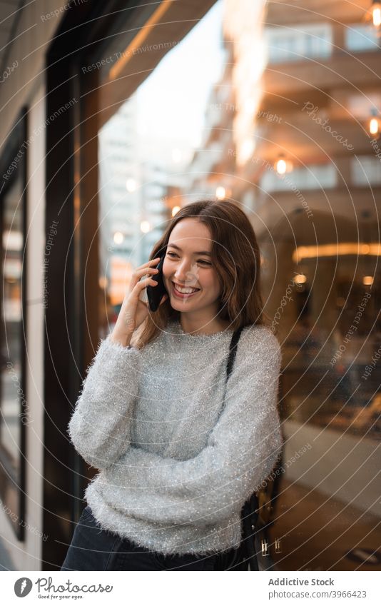 Woman talking on smartphone in city woman speak cheerful smile street discuss conversation female mobile call chat phone call using happy modern glass wall