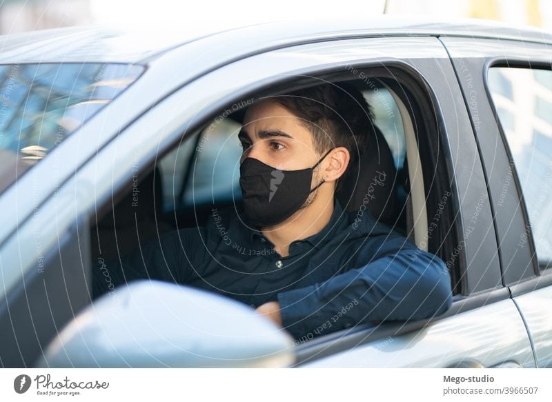 Young man driving his car. face mask drive sitting leisure road seat travel protective mask facemask city traffic medical mask outdoors concept healthcare adult