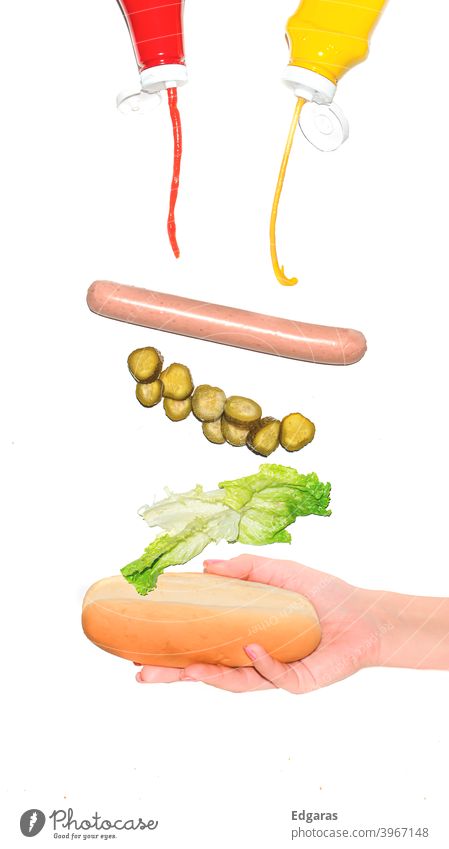 Holding hot dog with different ingredients flying Hot dog Grabbing hot dog Ingredients Flying Isolated Hand Ketchup Food Fresh Junk food Fast food Sausage