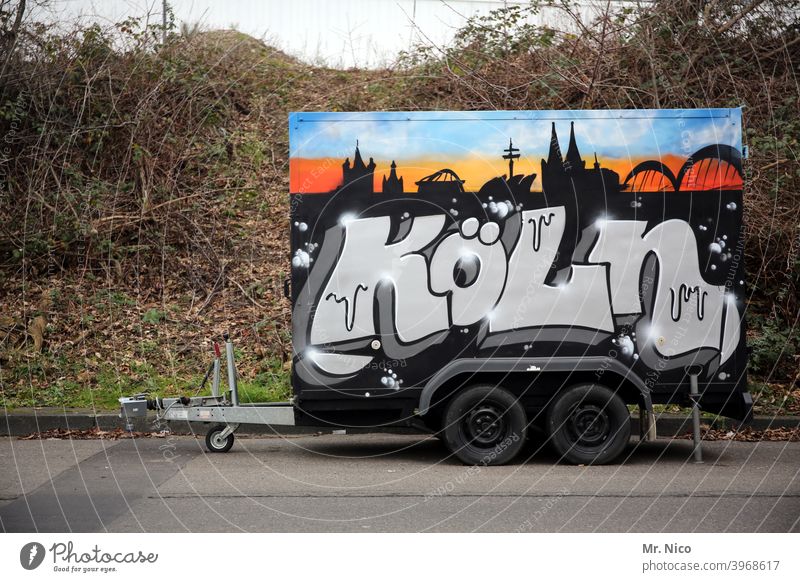 Trailer in Kölsch Logistics Means of transport Vehicle Mobility Trade Tire double axis Street turned off graffiti Cologne Characters Parking City panorama