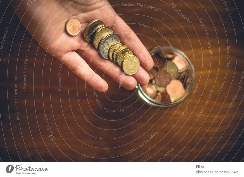 A person puts money coins in a jar. Saving. Coin Save Money Hand Bird's-eye view Glass Money box Euro Loose change Coins stop small livestock small change Wood